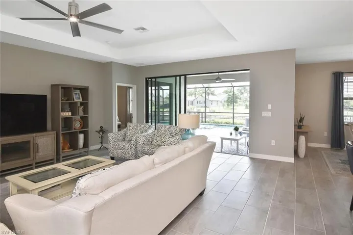 Living room with arched walkways, ceiling fan, a raised ceiling, and wood tiled floors