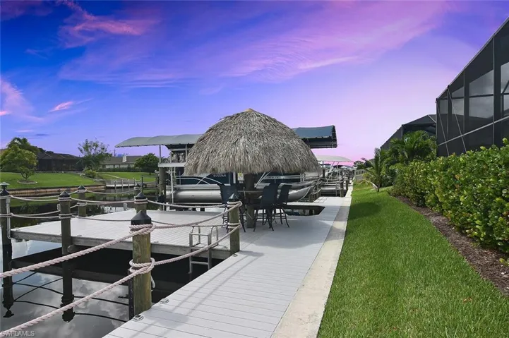 Dock with boat lift, a lanai, and a lawn