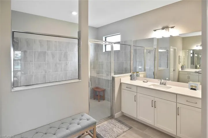 Bathroom with a shower stall, two vanities, and tile patterned flooring