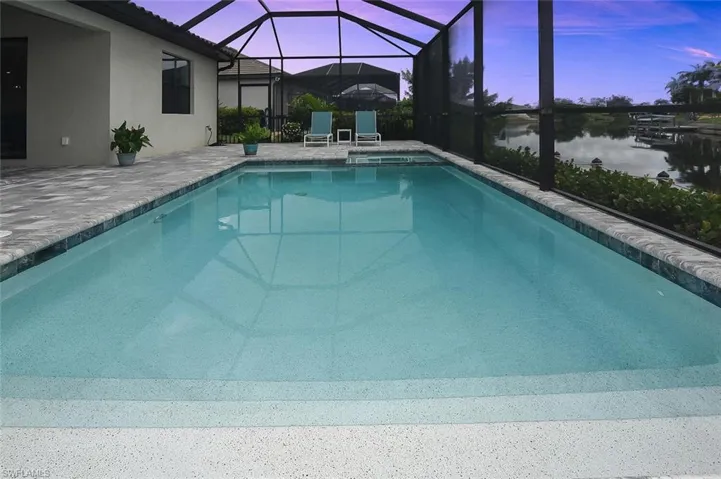 View of pool featuring a patio area, a pool with connected hot tub, and glass enclosure