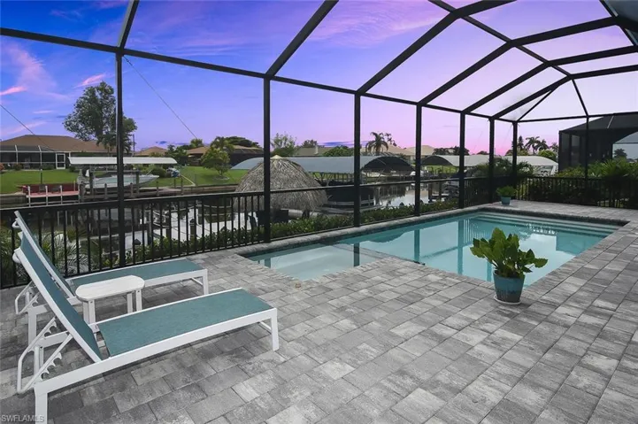 View of swimming pool featuring a patio area, a lanai, a pool with connected hot tub, and a water view
