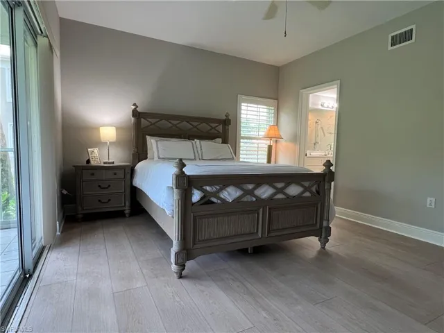 Bedroom featuring ceiling fan, wood-type flooring, ensuite bathroom, and access to exterior