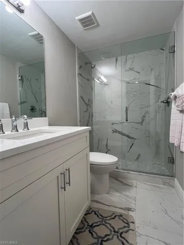 Bathroom featuring toilet, vanity, walk in shower, and tile patterned floors