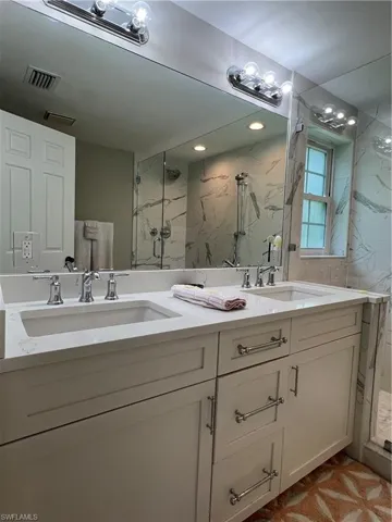 Bathroom featuring walk in shower and dual bowl vanity