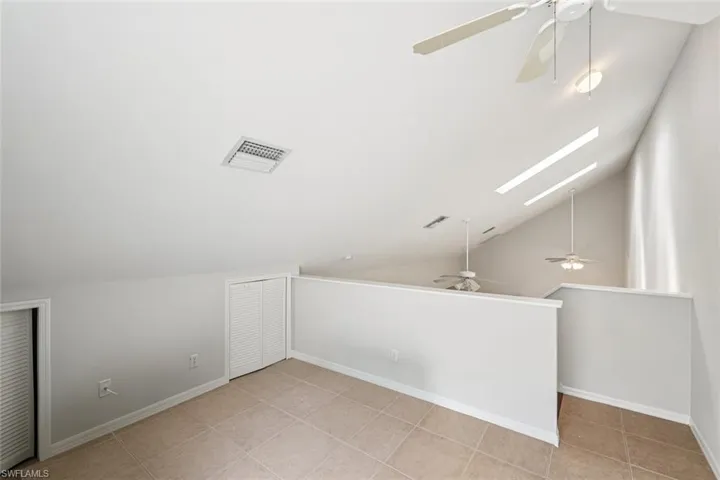 Bonus room with a ceiling fan, lofted ceiling, light tile patterned floors, and a skylight