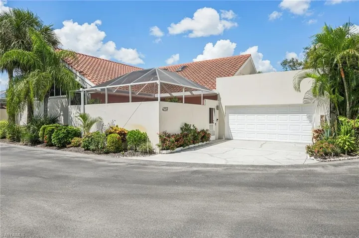 View of front of home featuring an attached garage, concrete driveway, a tiled roof, and stucco siding