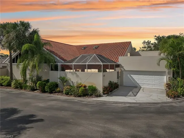 View of front of property featuring a garage, stucco siding, a tile roof, concrete driveway, and a lanai
