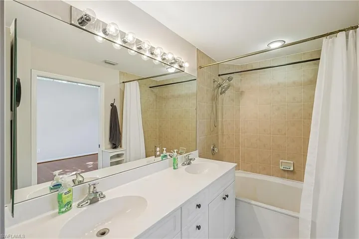 Bathroom featuring shower / bathtub combination with curtain and double vanity
