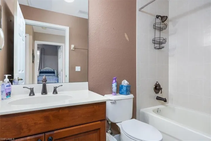 Full bathroom with a textured wall, tub / shower combination, and vanity