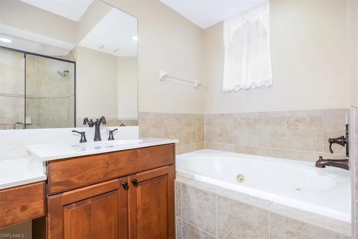 Full bath with vanity, a jetted tub, and a stall shower
