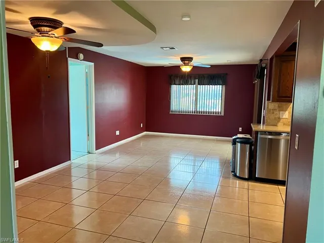 Empty room with ceiling fan and light tile patterned floors