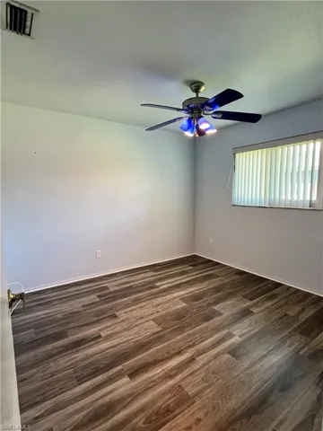 Spare room featuring dark wood finished floors and a ceiling fan