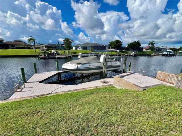 Dock area with a yard, boat lift, a residential view, and a water view
