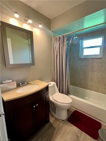 Full bath featuring shower / bath combo with shower curtain, vanity, wood finished floors, and a textured ceiling