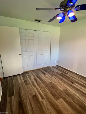 Unfurnished bedroom featuring dark wood-style floors, a closet, and a ceiling fan