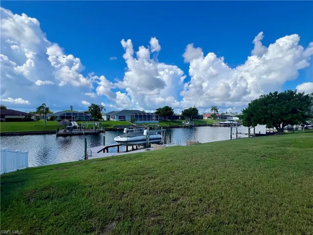 Dock area with a lawn, a water view, a residential view, and boat lift