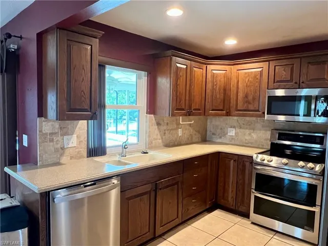 Kitchen with stainless steel appliances, light tile patterned floors, tasteful backsplash, and recessed lighting