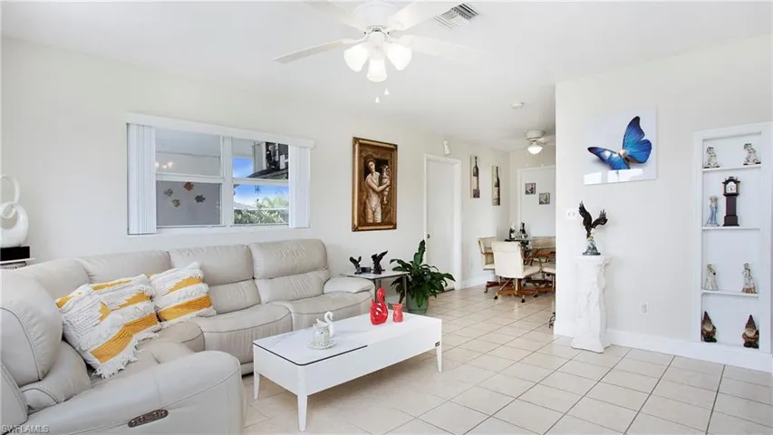 Living area with a ceiling fan, light tile patterned flooring, built in features, and baseboards