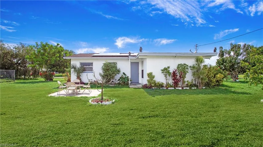 View of front of property with a patio area, roof mounted solar panels, and a front yard