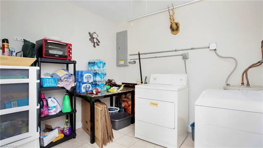 Large Laundry room off the dining room featuring electric panel, washing machine and clothes dryer, and light tile patterned floors