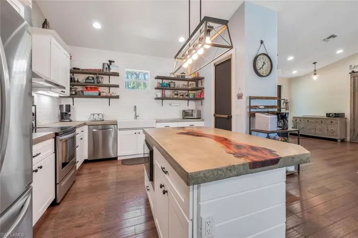 Kitchen featuring dark wood finished floors, open shelves, a sink, and stainless steel appliances