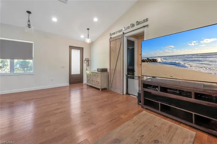 Entryway with a barn door, hardwood / wood-style flooring, lofted ceiling, and baseboards