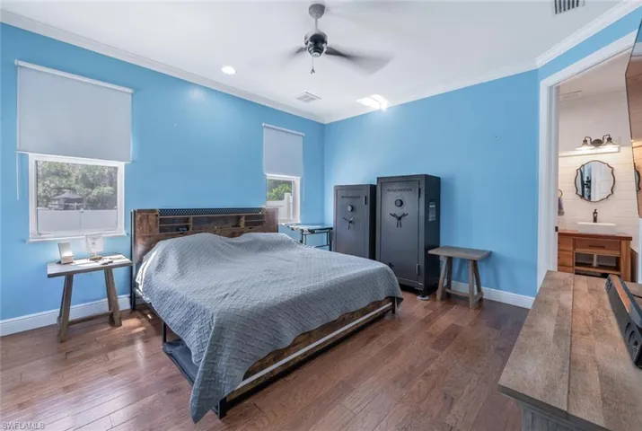 Bedroom with baseboards, visible vents, crown molding, and wood finished floors