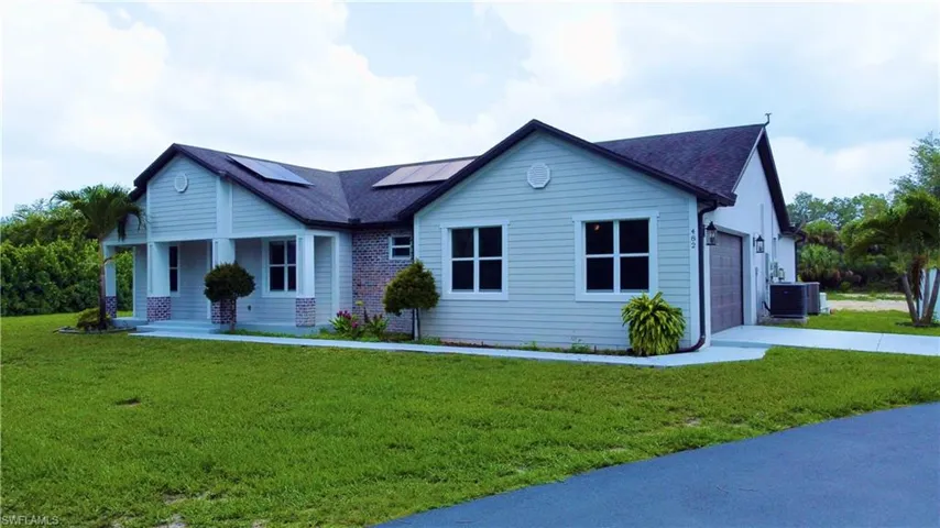 View of front of property featuring roof mounted solar panels, an attached garage, a front yard, and a porch