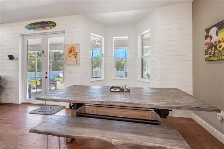 Dining area with french doors, baseboards, wooden walls, and wood finished floors