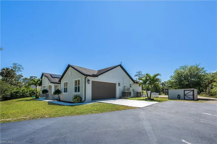View of front facade with driveway, a front yard, cooling unit, solar panels, and a garage