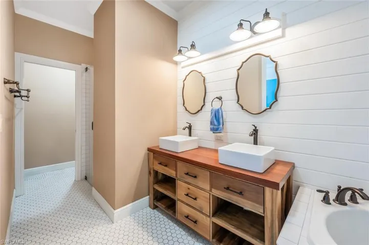 Bathroom featuring a tub to relax in, double vanity, ornamental molding, and a sink