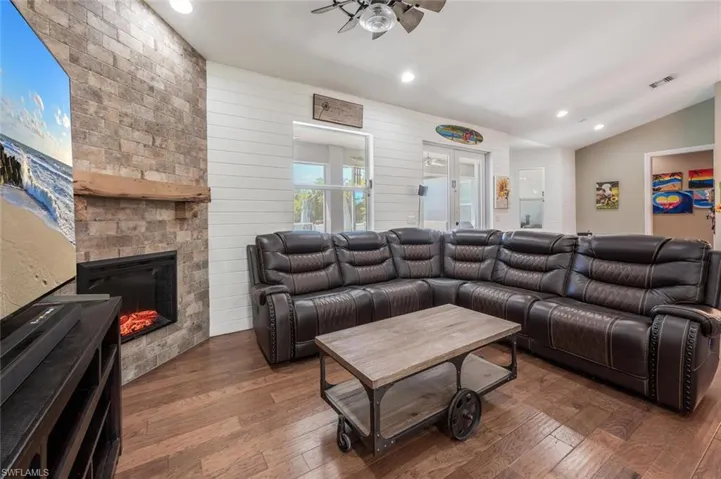 Living room with vaulted ceiling, visible vents, ceiling fan, and wood-type flooring