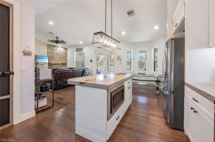 Kitchen with a center island, stainless steel appliances, visible vents, white cabinets, and a stone fireplace