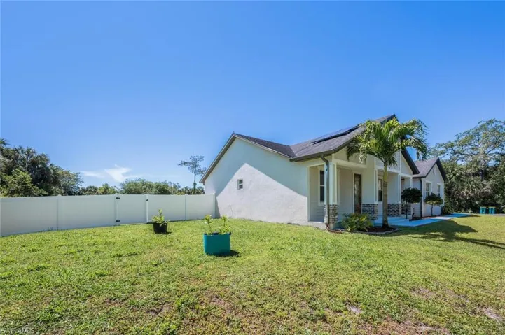 View of property exterior featuring a fenced backyard, stucco siding, a yard, and roof mounted solar panels