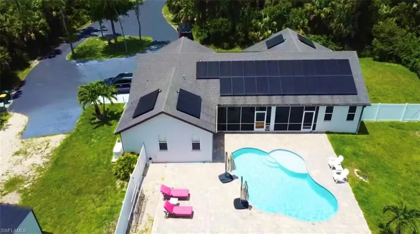 Rear view of house featuring roof mounted solar panels, a patio area, a fenced backyard, an outdoor pool, and stucco siding