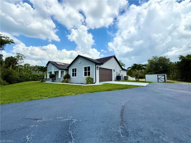 Single story home featuring driveway, a garage, a front lawn, and a storage shed