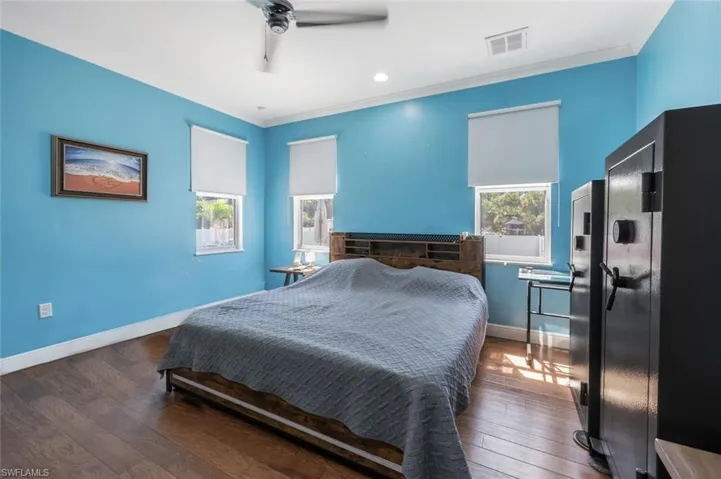 Bedroom with wood-type flooring, ornamental molding, and visible vents