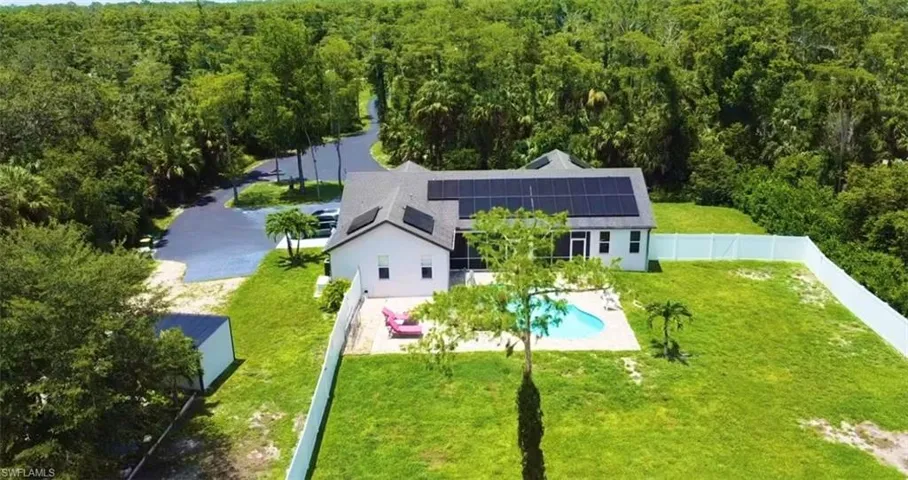 Aerial view of property and surrounding area featuring a forest and a pool area