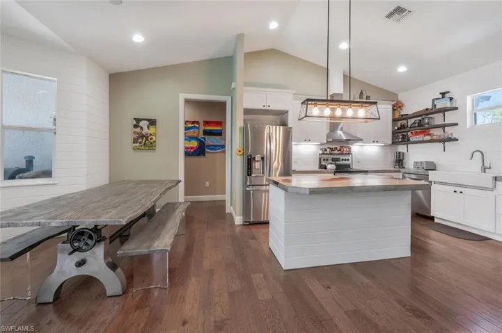 Kitchen with a sink, a kitchen island, dark wood finished floors, stainless steel appliances, and visible vents