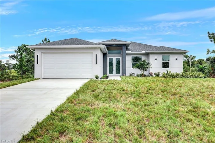 View of front of property featuring a garage and a front lawn