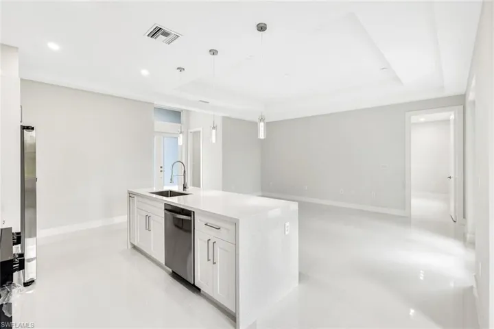 Kitchen featuring sink, white cabinetry, stainless steel appliances, a raised ceiling, and decorative light fixtures