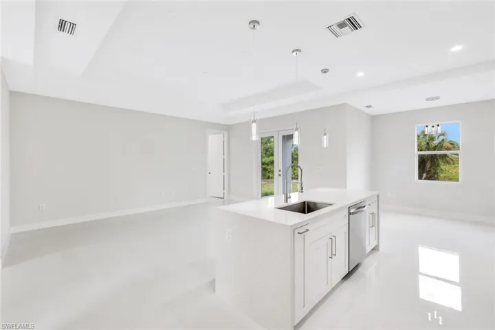 Kitchen with a kitchen island with sink, sink, a healthy amount of sunlight, and white cabinetry