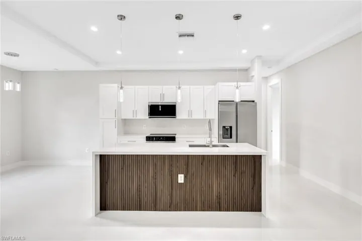 Kitchen featuring pendant lighting, stainless steel appliances, sink, and white cabinetry