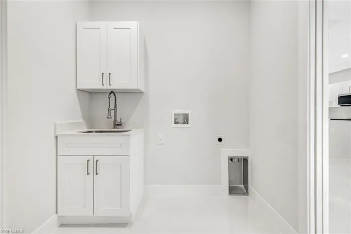 Washroom featuring cabinets, hookup for an electric dryer, hookup for a washing machine, and sink