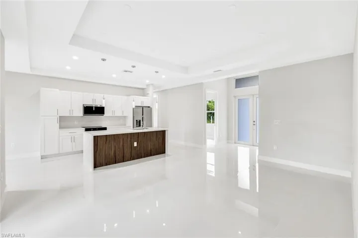 Kitchen with appliances with stainless steel finishes, a raised ceiling, a kitchen island, and white cabinets