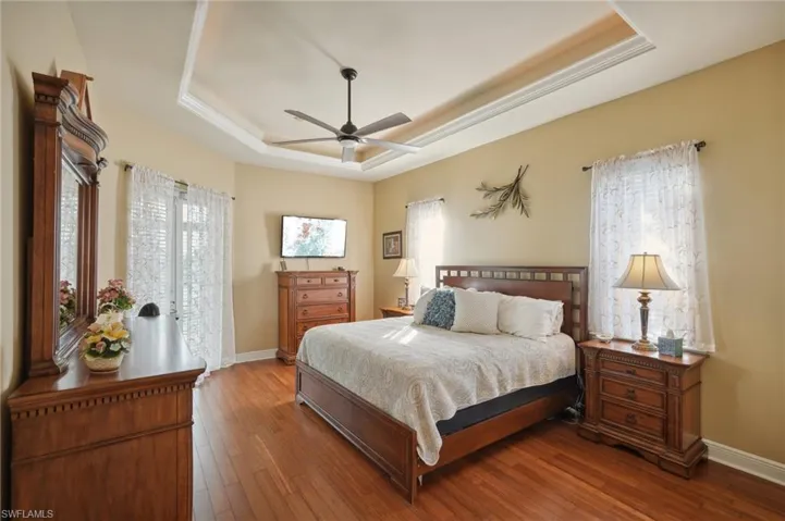 Bedroom featuring a raised ceiling, hardwood / wood-style flooring, and ceiling fan