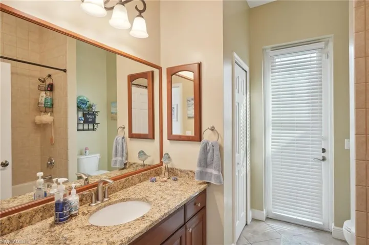 Full bathroom with toilet, tiled shower / bath, vanity, and tile patterned floors