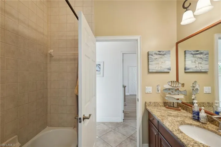Bathroom with vanity, tiled shower / bath combo, and tile patterned floors