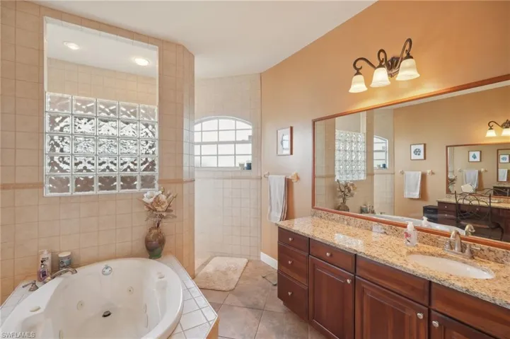 Bathroom featuring tile walls, vanity, tiled tub, and tile patterned floors