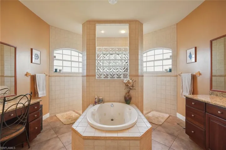 Bathroom featuring vanity, plus walk in shower, tile patterned floors, and tile walls
